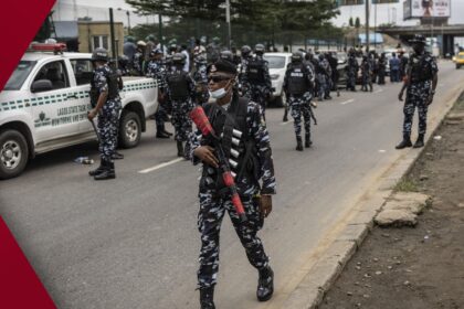 Armed Nigerian riot police in khaki uniforms and helmets confront a crowd of chanting protesters on a smoky Lagos street during political unrest