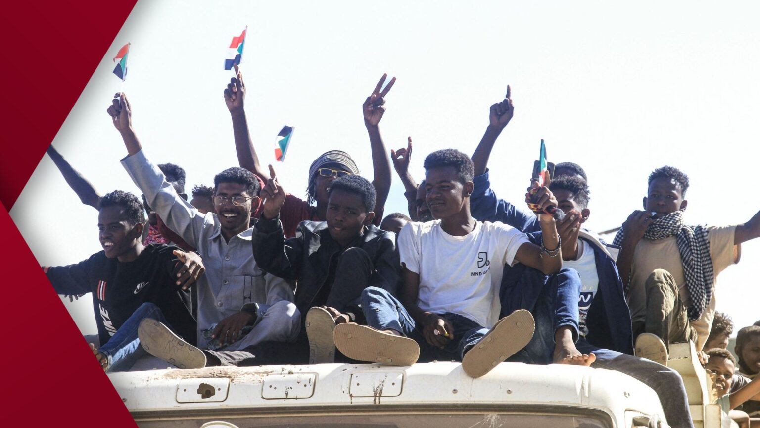 Crowd of Sudanese protesters marching through Khartoum street, waving national flags and banners, calling for end to military rule